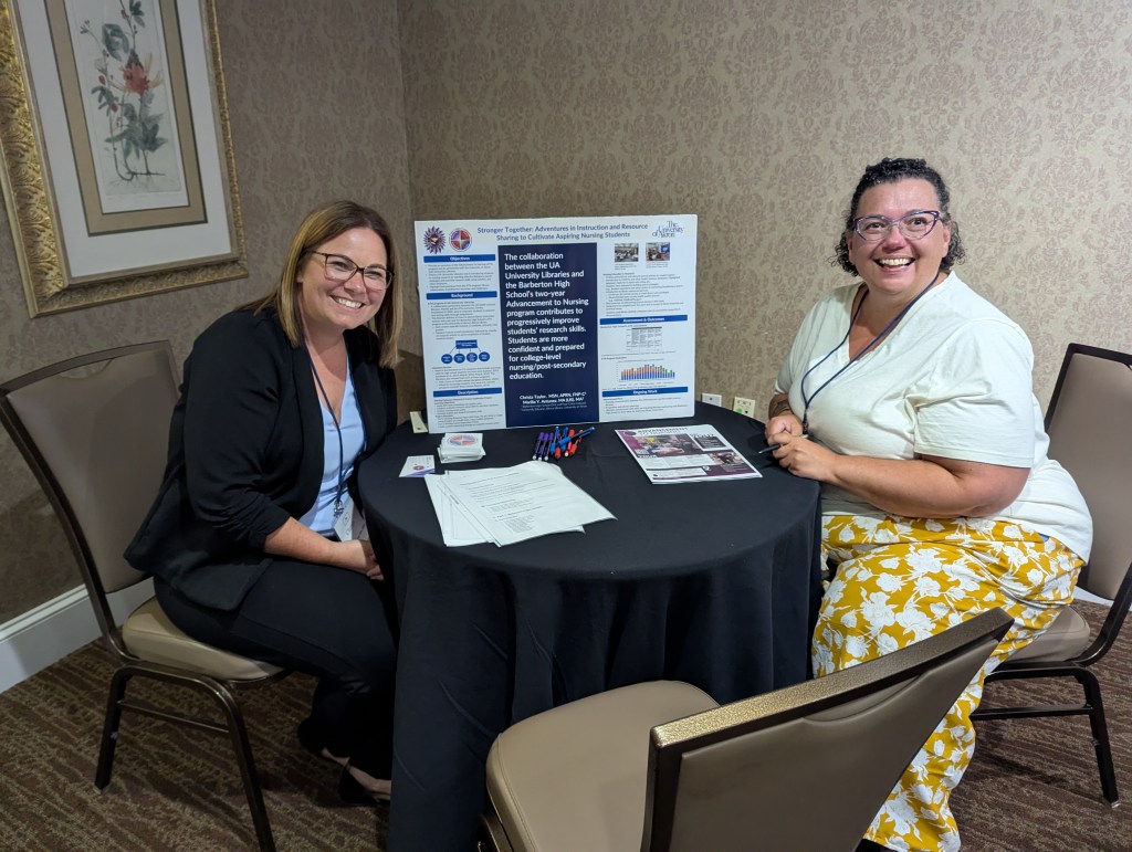 Two women smiling at a table during a poster session at the INANE Conference, with a poster titled 'Stronger Together: Advancements in Instruction and Resource Sharing for Nursing Students' in the background.