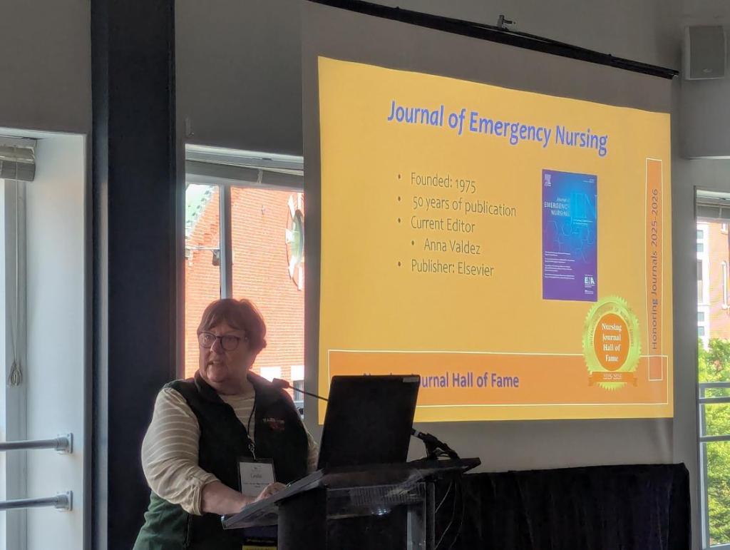 A speaker presenting at the Nursing Journal Hall of Fame Ceremony during the INANE Conference, with a slide showcasing the Journal of Emergency Nursing, including its founding year, current editor, and publisher.
