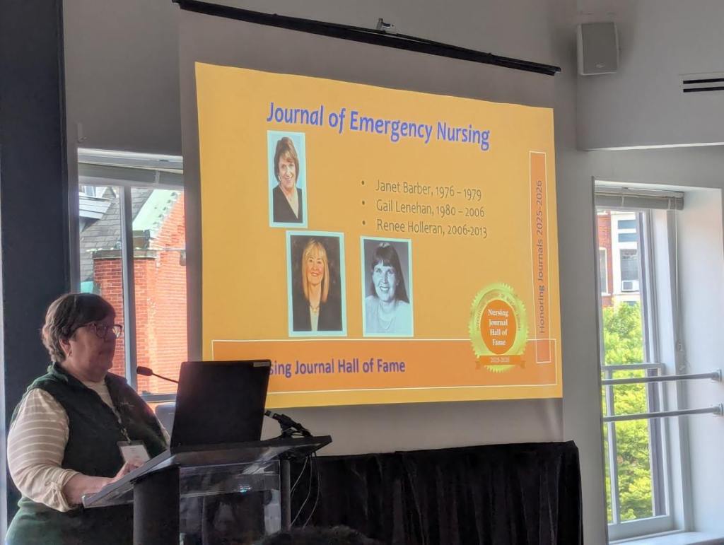 A speaker presenting at the Nursing Journal Hall of Fame Ceremony, with a slide displaying notable figures honored in the Journal of Emergency Nursing.